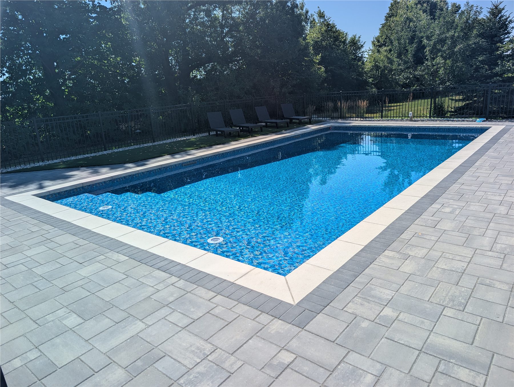 Finished Einstein pool with a blue liner and gray paver patio
